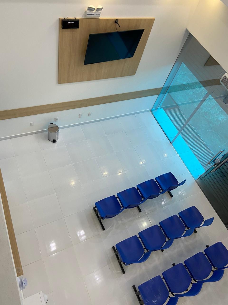 Sala de espera vista do mezanino, com pé-direito alto e luz natural
