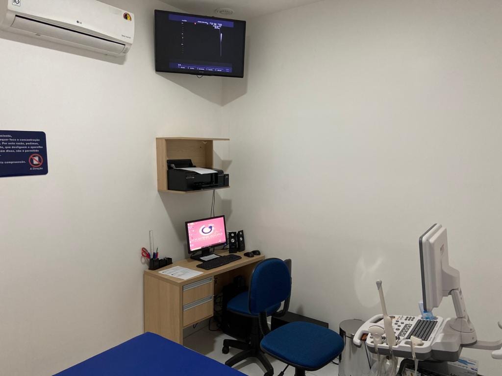Sala de ultrassonografia, com aparelho de ultrassom, maca e monitor de apoio